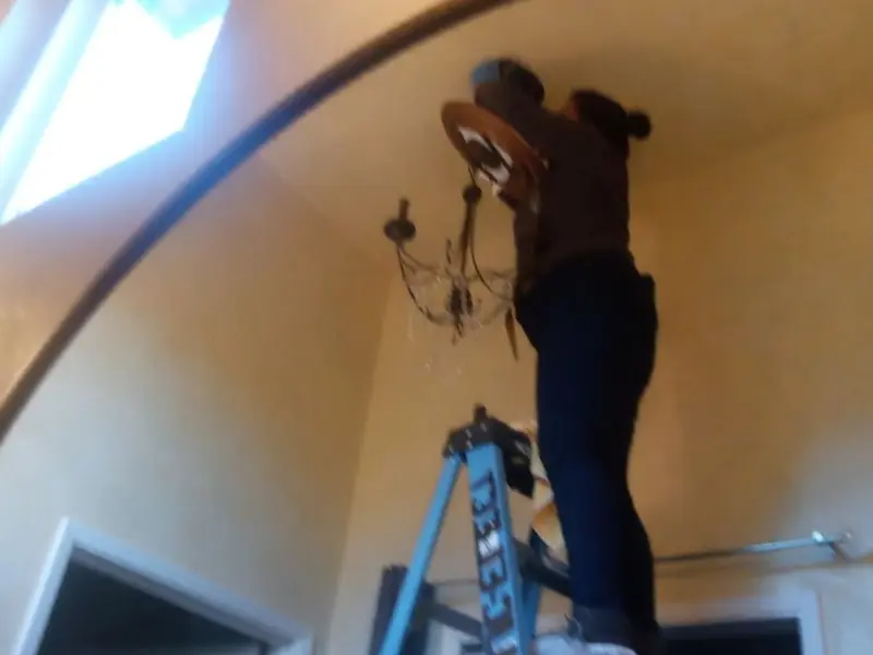 Electrician installing a chandelier in a Post Falls residence